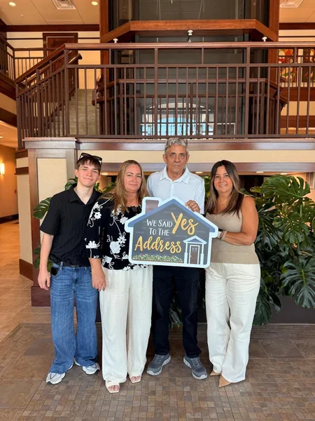 A family of four at a title company holding a sign reading We Said Yes To The Address