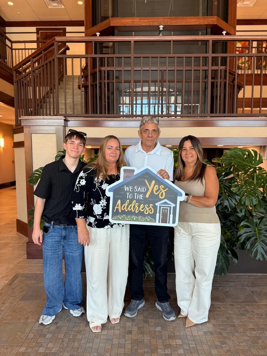 A family of four at a title company holding a sign reading We Said Yes To The Address