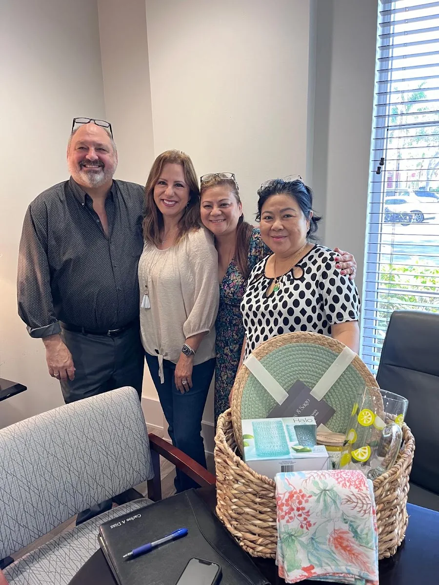 Four people standing behind a closing table with a woven gift basket of housewarming presents
