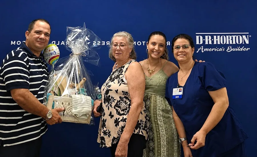 A buyer holding a wrapped gift basket beside three others in front of a D.R. Horton backdrop